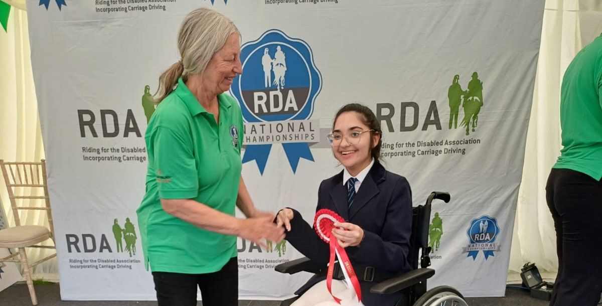Student in wheelchair receiving rosette