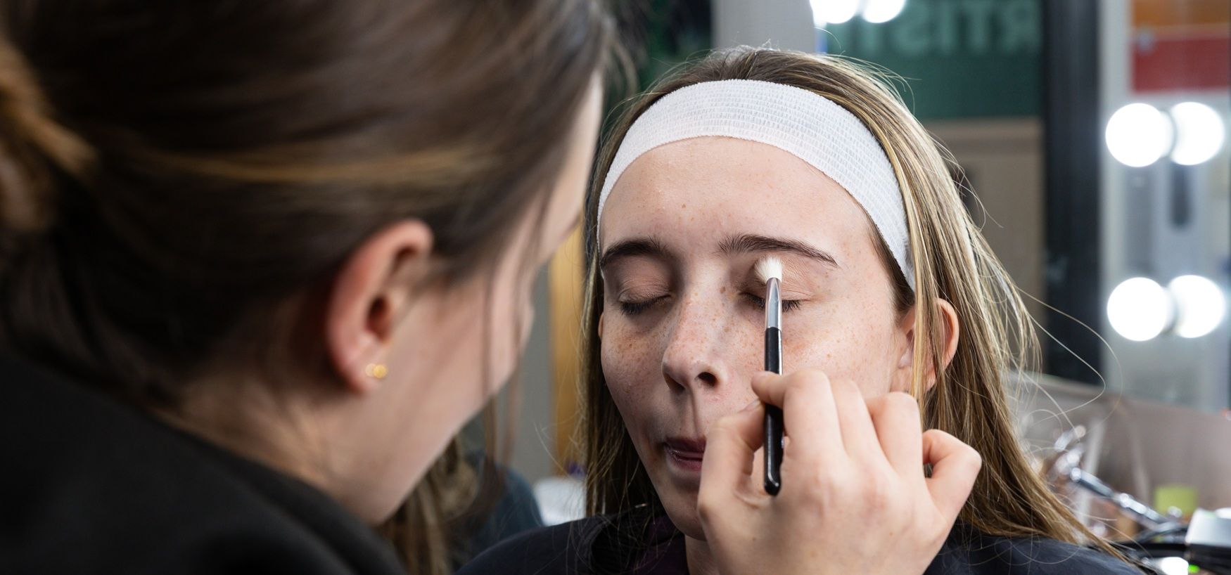 Student putting make up on another student