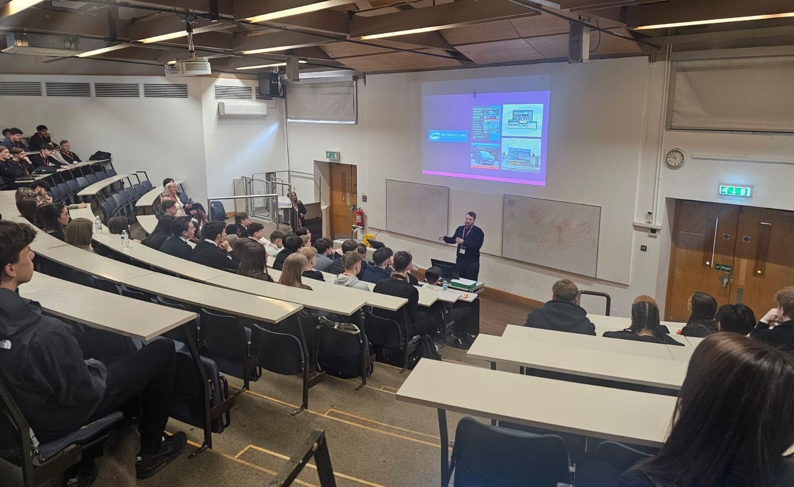 Person in lecture theatre talking to students