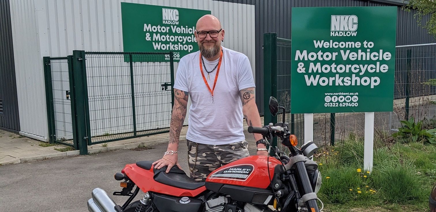 Man with motorbike in front of vehicle workshop