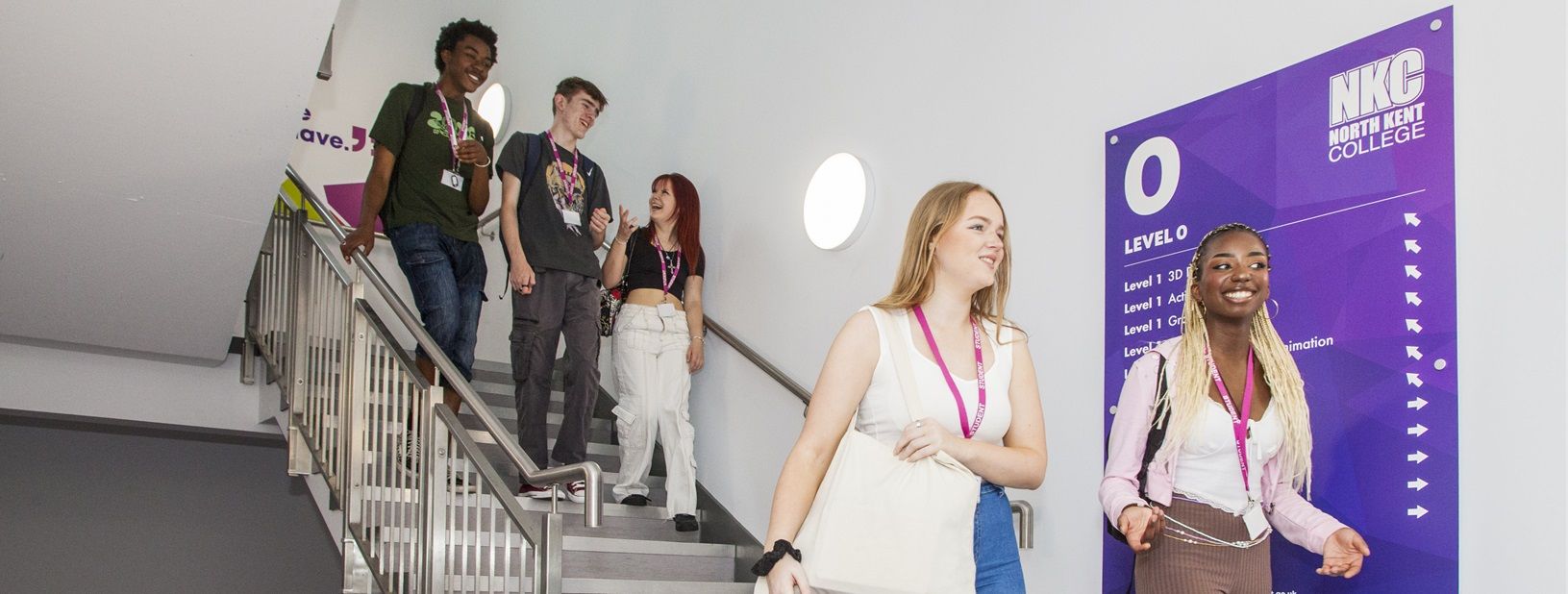 Students talking and walking down stairs next to NKC sign
