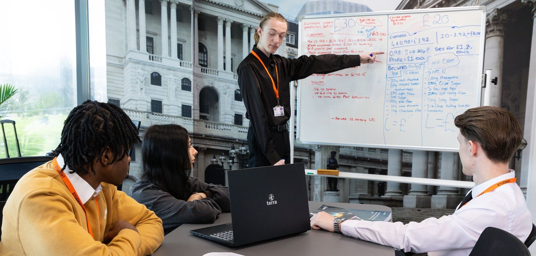 Student pointing at whiteboard with other students looking on