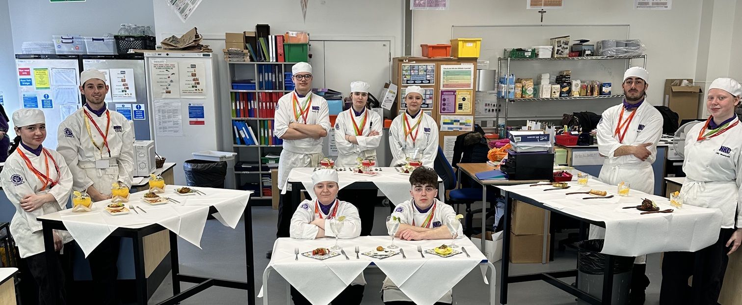 Catering students in chef's uniform around table