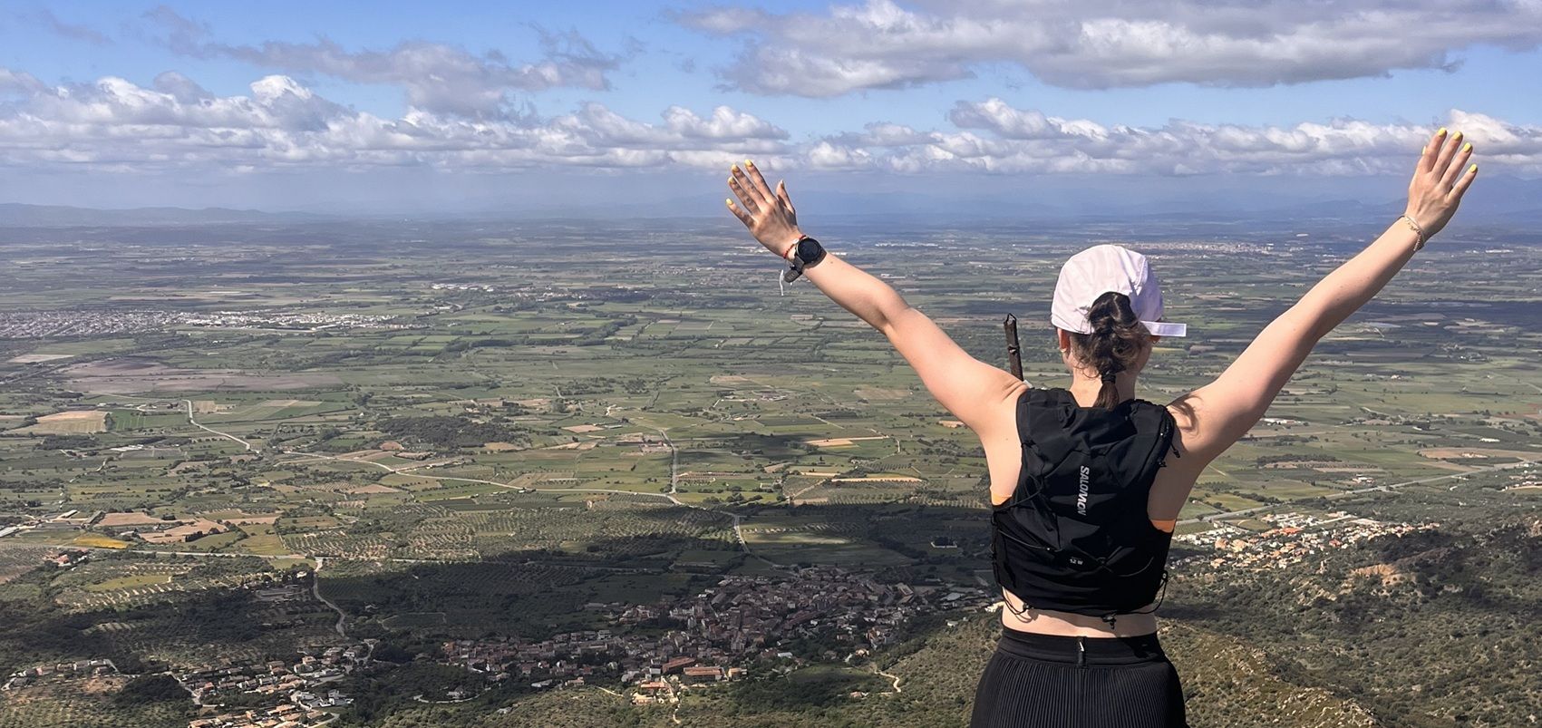 Student looking across scenic landscape with hands in air