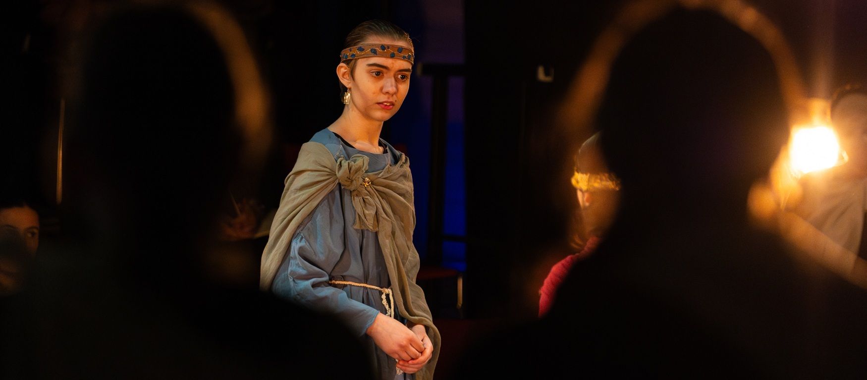 Young student on stage with silhouettes of two students in front of her