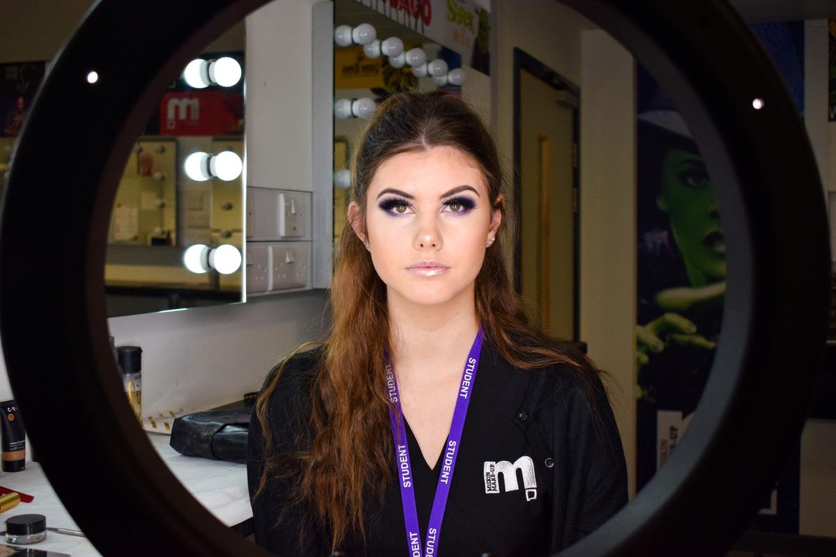female make-up student looking into ring light
